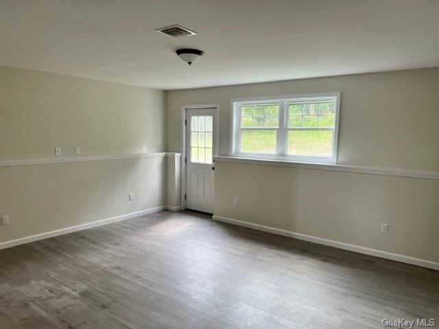 empty room featuring visible vents, baseboards, and wood finished floors