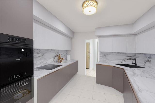 kitchen with light stone countertops, sink, gray cabinets, decorative backsplash, and black appliances