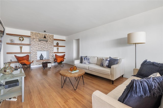 living room with a stone fireplace and light hardwood / wood-style flooring