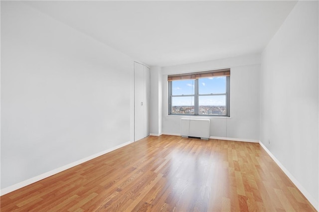 spare room featuring radiator heating unit and light hardwood / wood-style flooring