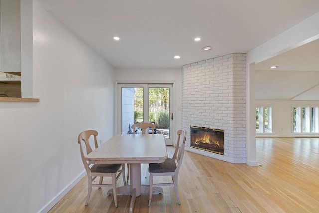 dining room with light hardwood / wood-style flooring and a brick fireplace