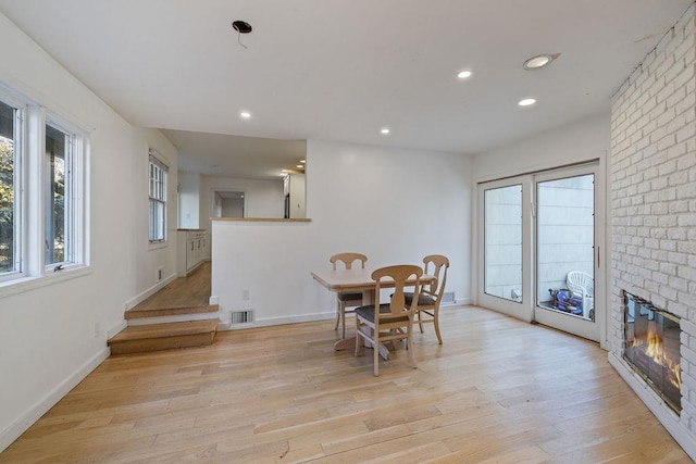 dining area with light wood-type flooring and a brick fireplace