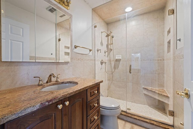 bathroom with vanity, backsplash, toilet, tile walls, and walk in shower