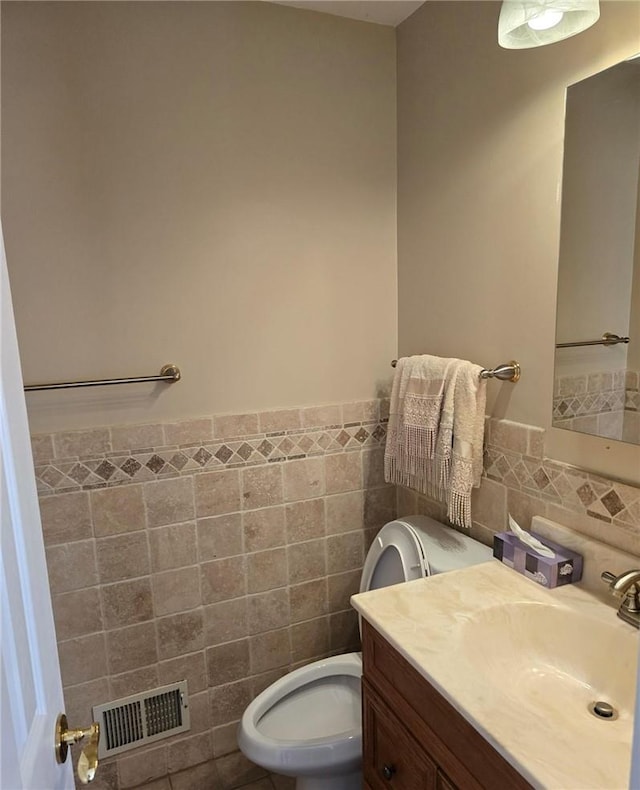 bathroom featuring tile patterned flooring, vanity, toilet, and tile walls