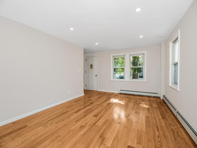 empty room with light hardwood / wood-style floors and a baseboard heating unit