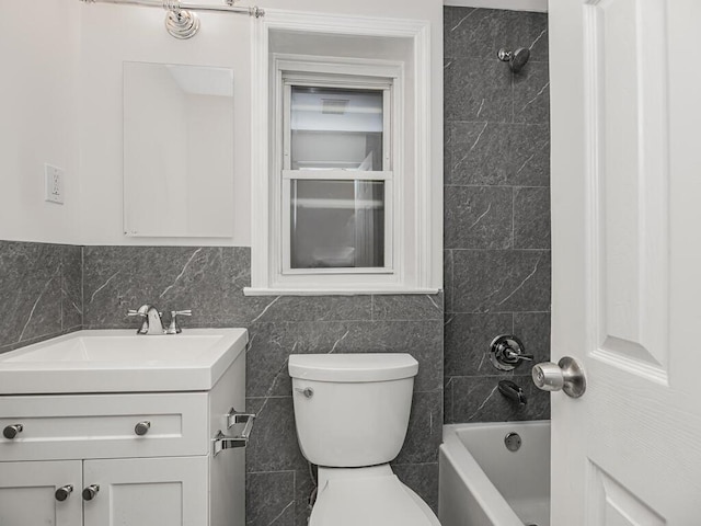 full bathroom featuring tile walls, vanity, tiled shower / bath combo, and toilet