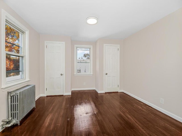 empty room featuring radiator and dark hardwood / wood-style flooring