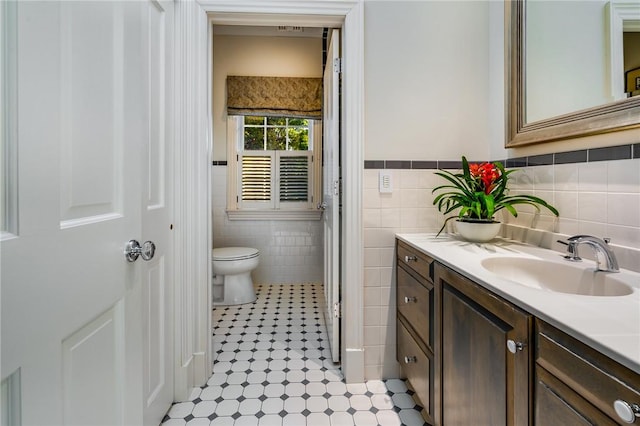 bathroom featuring vanity, toilet, and tile walls