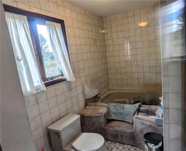 bathroom featuring a bathtub, toilet, and tile walls