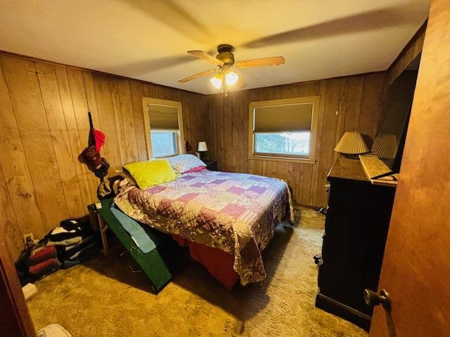 bedroom with ceiling fan, wooden walls, and carpet floors