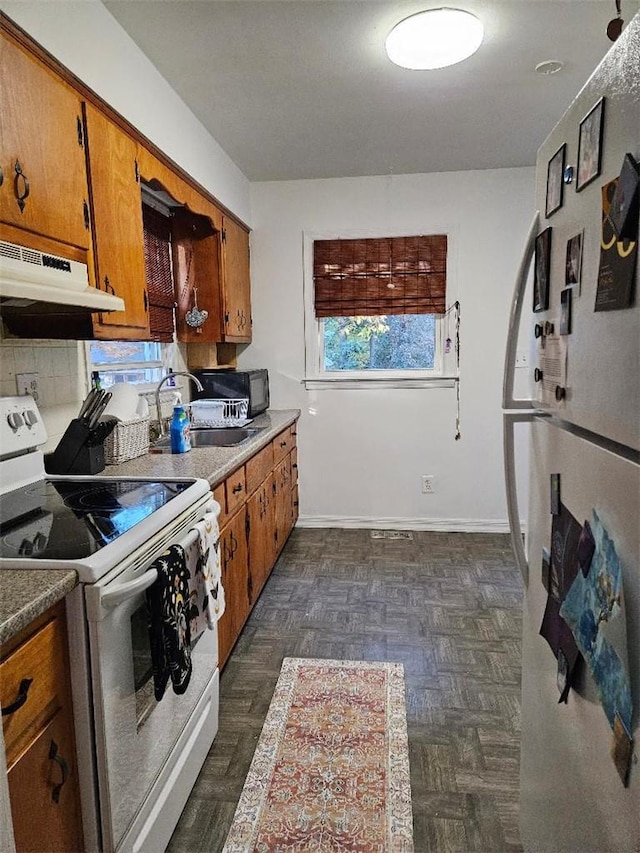 kitchen featuring dark parquet floors, tasteful backsplash, white range with electric stovetop, and sink