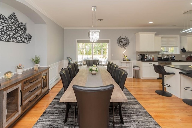 dining space with crown molding, light hardwood / wood-style flooring, a baseboard radiator, and an inviting chandelier