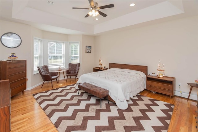 bedroom featuring a tray ceiling, ceiling fan, and hardwood / wood-style flooring