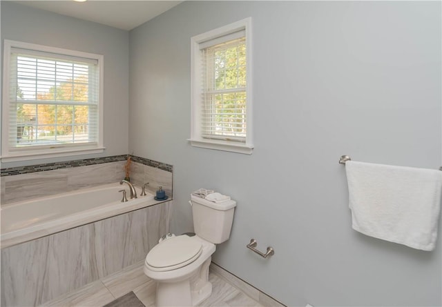 bathroom featuring tile patterned floors, a relaxing tiled tub, and toilet