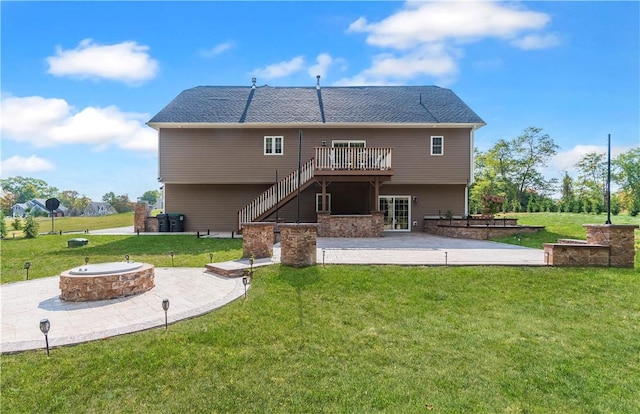 rear view of house with a wooden deck, an outdoor fire pit, a patio area, and a lawn