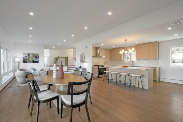 dining space with sink, plenty of natural light, a chandelier, and light hardwood / wood-style flooring