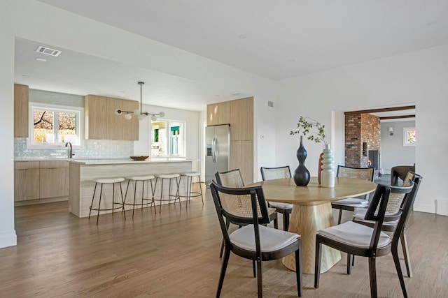 dining area with a chandelier, wood-type flooring, and sink