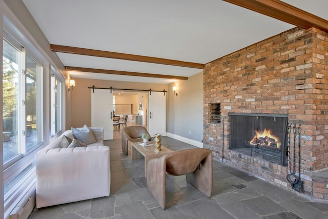 living room featuring beam ceiling, a barn door, and a brick fireplace