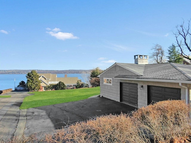 garage featuring a lawn and a water view