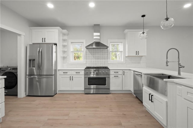 kitchen featuring white cabinets, appliances with stainless steel finishes, pendant lighting, and wall chimney range hood