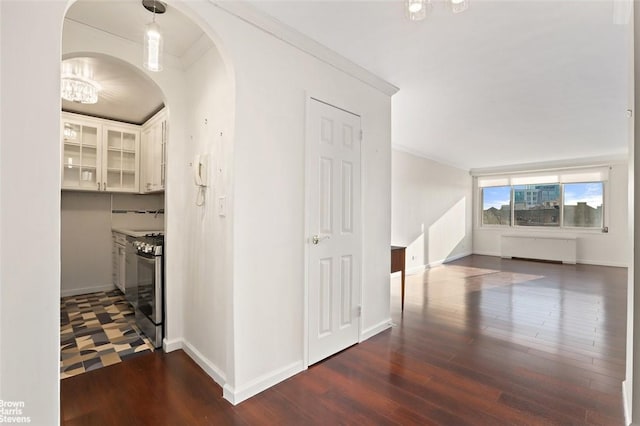 hallway with radiator heating unit, dark hardwood / wood-style flooring, and crown molding