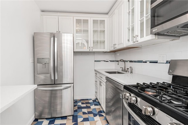 kitchen with decorative backsplash, white cabinetry, sink, and appliances with stainless steel finishes