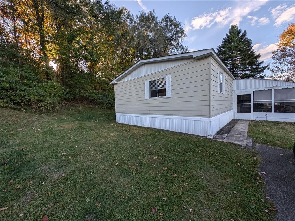 view of home's exterior featuring a lawn and a sunroom