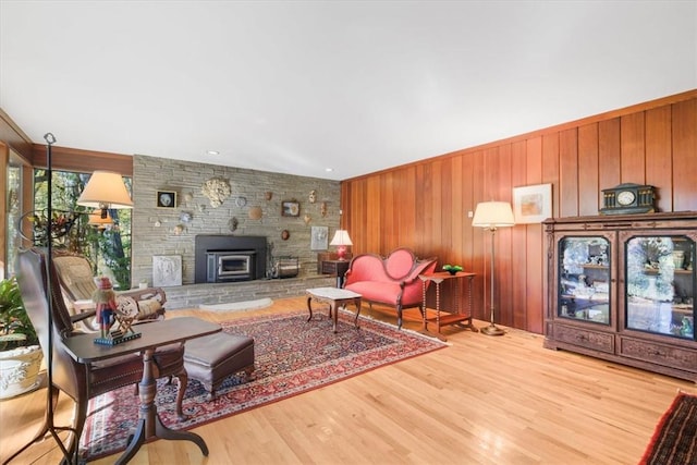 living room with a wood stove, wooden walls, and hardwood / wood-style floors