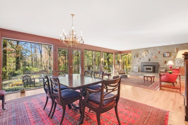 dining area featuring a wood stove, light wood-type flooring, and an inviting chandelier