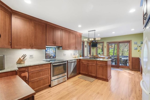 kitchen featuring sink, hanging light fixtures, light wood-type flooring, kitchen peninsula, and stainless steel appliances