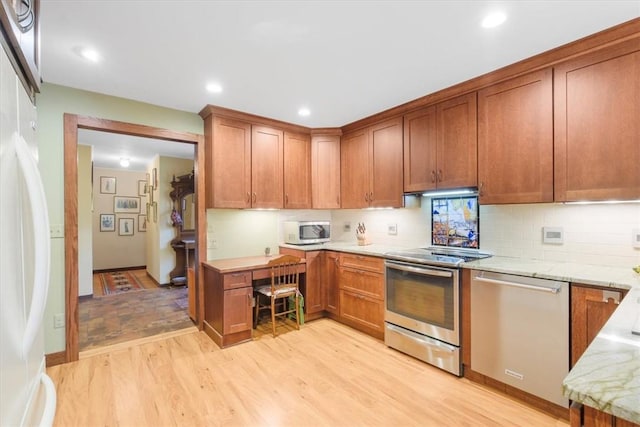 kitchen with decorative backsplash, appliances with stainless steel finishes, light hardwood / wood-style floors, and light stone counters