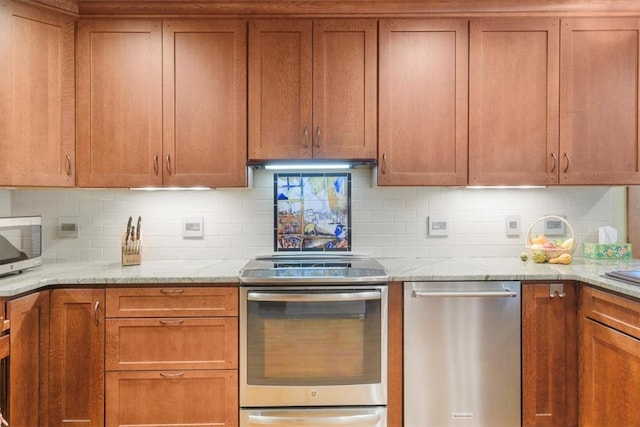 kitchen with light stone countertops, backsplash, and stainless steel appliances