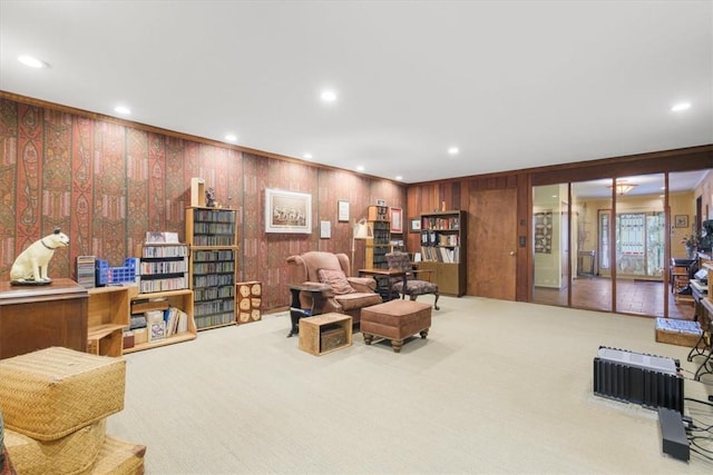 carpeted living room with wood walls and crown molding