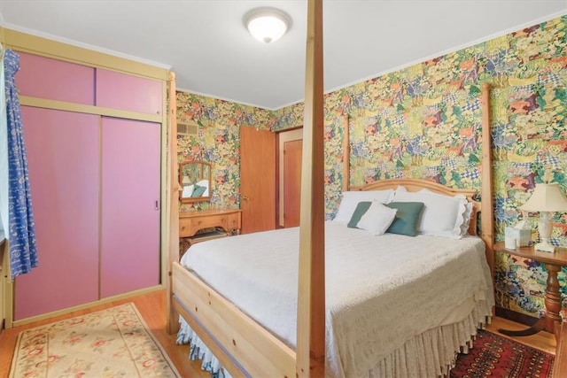 bedroom with hardwood / wood-style floors, a closet, and crown molding