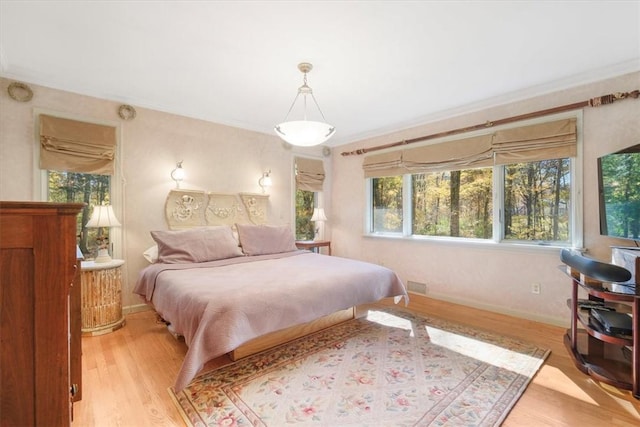 bedroom with crown molding and light hardwood / wood-style flooring