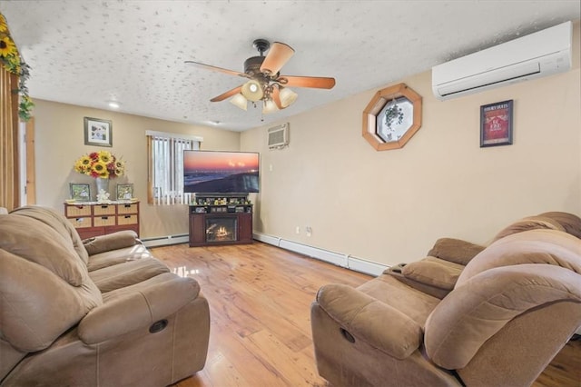 living room featuring baseboard heating, ceiling fan, a wall unit AC, and wood-type flooring