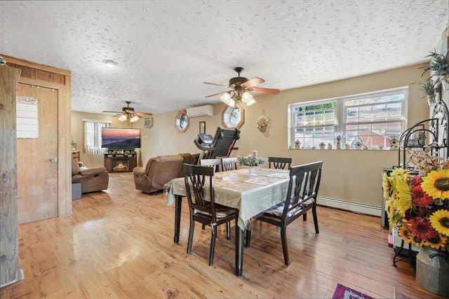 dining room featuring a wall mounted air conditioner, a baseboard heating unit, light hardwood / wood-style flooring, ceiling fan, and a textured ceiling