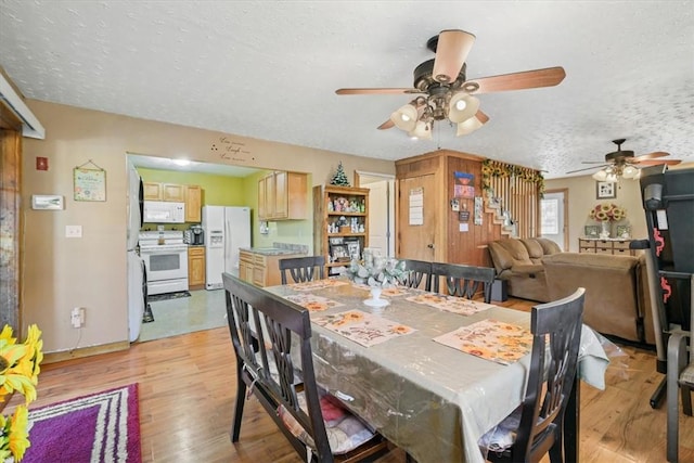 dining area with a textured ceiling, light wood-type flooring, and ceiling fan