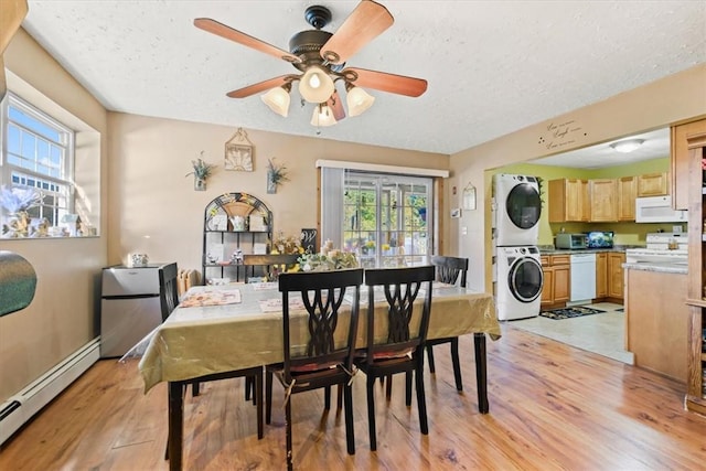 dining area featuring light hardwood / wood-style floors, plenty of natural light, stacked washing maching and dryer, and a baseboard heating unit