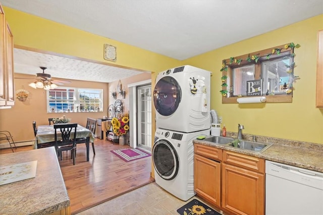 laundry room with sink, light hardwood / wood-style flooring, ceiling fan, baseboard heating, and stacked washer / drying machine