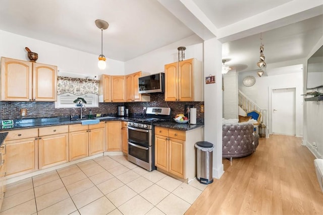 kitchen featuring decorative light fixtures, light hardwood / wood-style flooring, appliances with stainless steel finishes, and tasteful backsplash