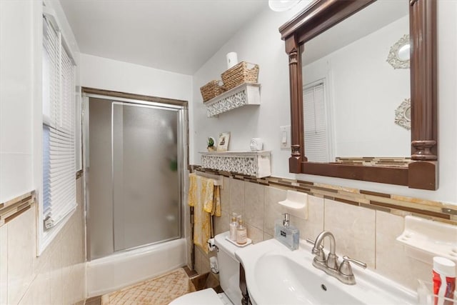 full bathroom featuring toilet, combined bath / shower with glass door, sink, and tasteful backsplash