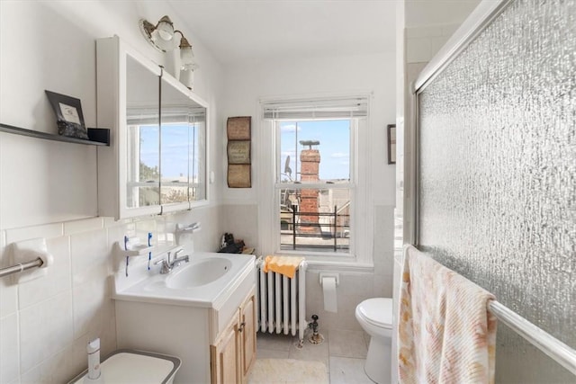 bathroom featuring tile patterned flooring, toilet, radiator, and tile walls