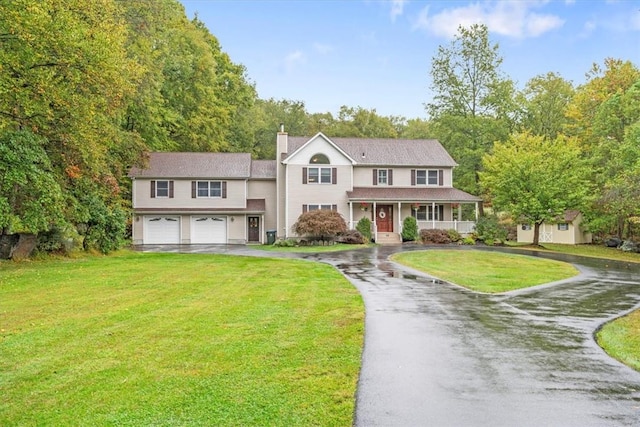 colonial home featuring covered porch, a garage, and a front lawn