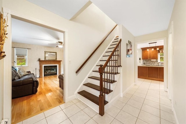 staircase featuring baseboard heating, ceiling fan, and wood-type flooring