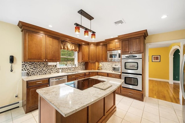 kitchen featuring a center island, sink, light stone countertops, decorative light fixtures, and stainless steel appliances