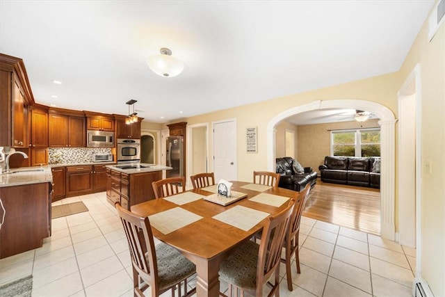 dining area with baseboard heating, ceiling fan, sink, and light tile patterned flooring