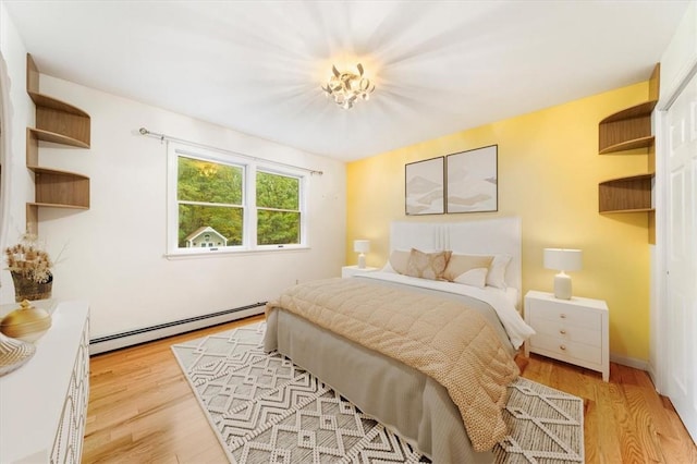 bedroom with baseboard heating and light hardwood / wood-style flooring