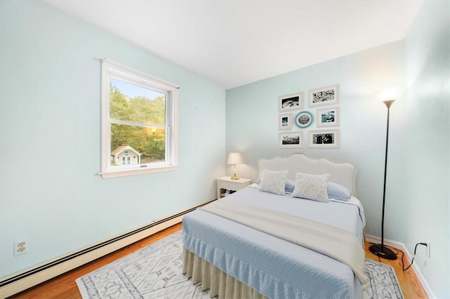 bedroom with a baseboard radiator and light wood-type flooring