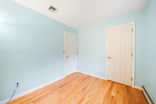 unfurnished room featuring light wood-type flooring and baseboard heating